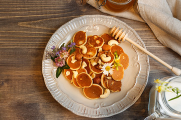 Grey plate with mini pancakes, on a dark wooden background, top view horizontally with space