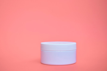 Round, white, plastic cosmetic jar, layout isolated on a pink background.