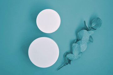 Round, white, plastic cosmetic jar, layout isolated on blue background.