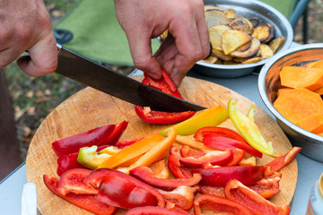 Cutting red and yellow sweet peppers on wooden cutting board