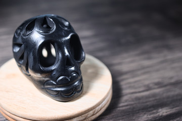 Figure of black, skull-shaped mud on dark wood