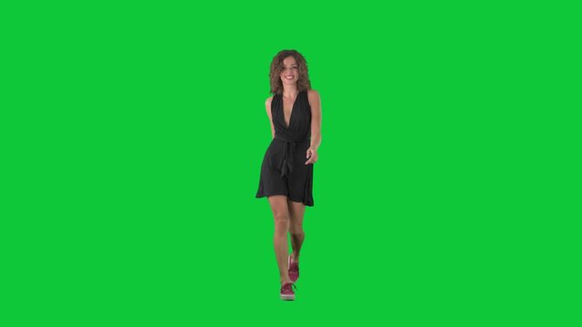 Joyful jumpy young woman bouncing and hopping while walking on green screen chroma key background. 