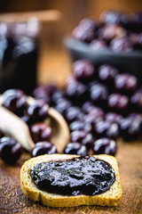 jar of Brazilian fruit jam, called jabuticaba or jaboticaba, on a rustic wooden table.
