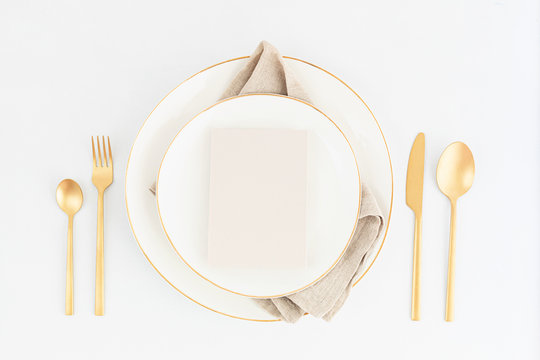 Festive christmas, wedding, birthday table setting with golden cutlery and porcelain plate
