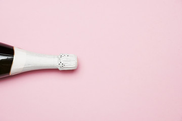Champagne bottle lying on pink background. flat lay. party concept