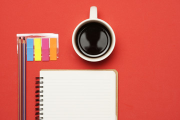 work space with notebook, stickers and coffee n on red background. flat lay.