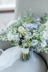 Bridal bouquet. The bride's bouquet. Beautiful bouquet of white, blue, pink flowers and greenery, decorated with long silk ribbon lies on a gray textural background