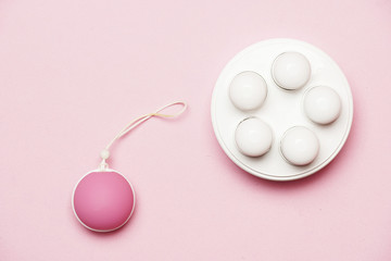 pelvic floor weights and ball on a pink background. female health care concept. flat lay