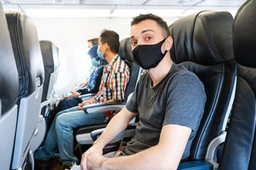 Airplane passengers are wearing medical masks on their faces. Air travel during the coronavirus pandemic. Airlines requirements.