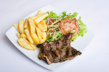 Chuleta asada con ensalada y papas fritas