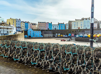 A view over lobster pots across the harbour in Tenby bathed in sunshine at low tide