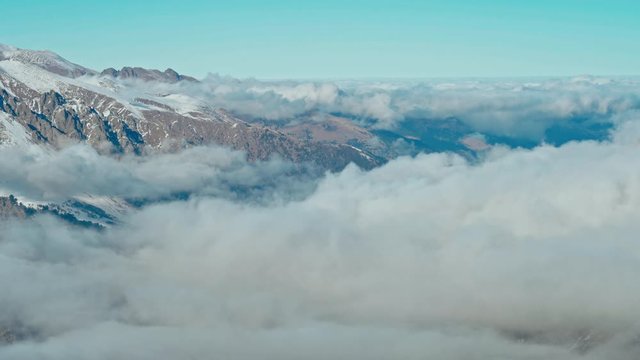 Snow capped mountains above clouds in a blue sky in sunny weather