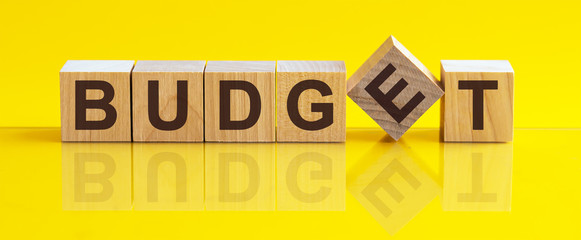 Word BUDGET is made of wooden building blocks lying on the table and on a light yellow background. Concept