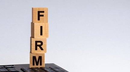 Word FIRM is made of wooden building blocks on a light grey background. Concept