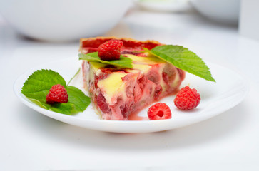 raspberry piroke on a white table, garnished with raspberries and raspberry leaves.
