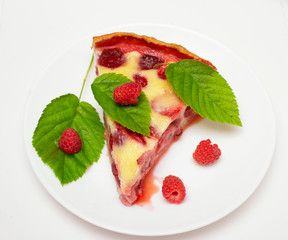 raspberry piroke on a white table, garnished with raspberries and raspberry leaves.