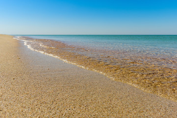 Empty sandy beach and clear blue sea. Seaside and calm sea. Focusing on the foreground.