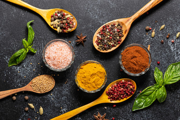 Assortment of spices and herbs on black rustic background top view.