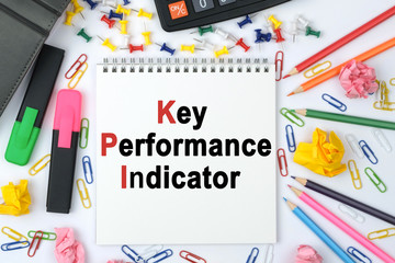 On the table is a calculator, diary, markers, pencils and a notebook with the inscription - Key Performance Indicator