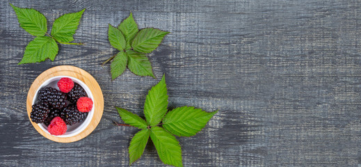 ripe blackberry with leaves on on dark blue wooden background, rustic