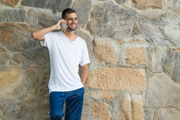 Fototapeta premium young man with mobile phone on the wall outdoors