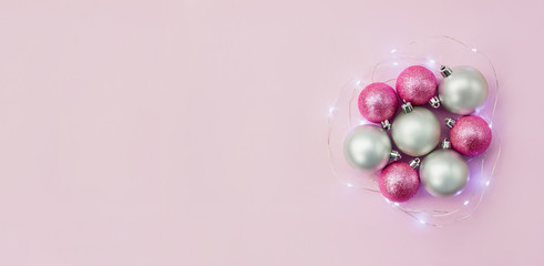 Pink and silver balls surrounded by Christmas light garland. Happy New Year concept. Selective focus. Copy space