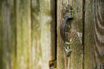 Old iron handle on a wooden entrance door. Retro, vintage.
