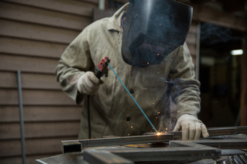 welder welds metal with an electric welding machine. metal works in the workshop close up. 