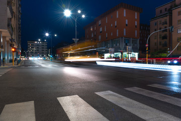 Fototapeta premium Timelapse view of traffic at an urban night intersection. Urban movement in the Italian city in the evening.