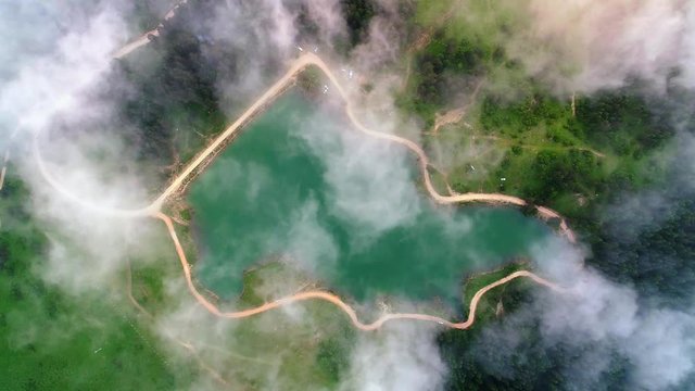 White clouds rolling over beautiful mountain lake surrounded with pine trees. Drone aerial top down view. Mountain and forest lake on Karagol Plateau, Tarakli Village in Sakarya, Turkey 
