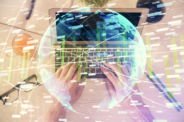 Double exposure of man's hands typing over computer keyboard and business theme hologram drawing. Top view. Financial markets concept.