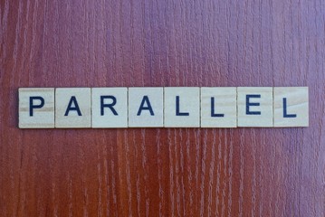 gray word parallel made of wooden square letters on brown table