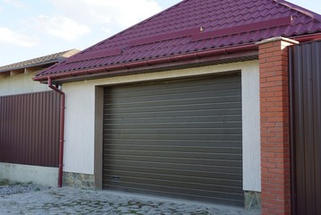 garage with brown gates under a red tiled roof on the street
