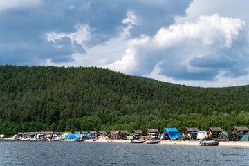 Fototapeta premium Russia, Irkutsk region, Baikal lake, July 2020: camping tents and tourists on baikal shore, from water view