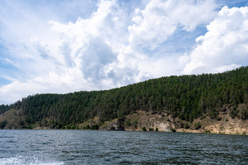Russia, Irkutsk region, Baikal lake, July 2020: boast splash traces on water, cliffs and mountains in distance
