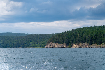 Russia, Irkutsk region, Baikal lake, July 2020: summer vacation on baikal river, thicks green forest on the shore, cloudy sky