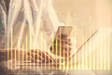 Double exposure of financial graph sketch hologram and woman holding and using a mobile device. Stock exchange concept.
