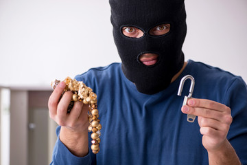Male robber stealing valuable things from the house