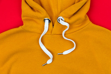 Close up of hoodie lace of a orange sweatshirt on red background. Close up