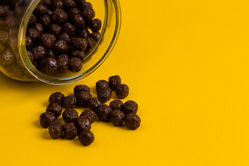 Chocolate cereal cornflakes spilling to the yellow background