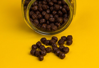 Chocolate cereal cornflakes spilling to the yellow background
