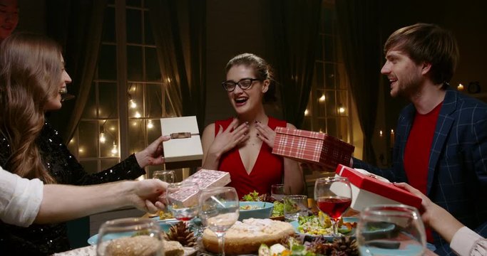 Group of multiethnic friends celebrating birthday. Beautiful caucasian girl is given gifts and blows out candle on special cake - happy people, holidays, friendship concept 4k footage