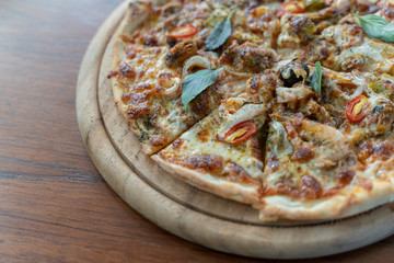 Homemade pizza with tomatoes, olives, salami, mozzarella cheese and seafoog on wooden rustic table.