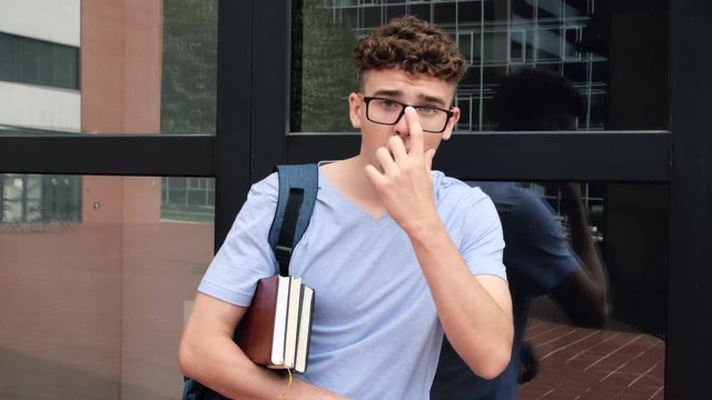 Portrait of school nerd Surprised student, expresses disagreement  and saying no. with book on hands near university campus.