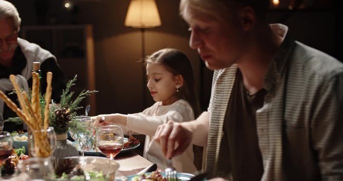 Happy family celebrating christmas at home. Family members together at holiday dinner table talking, smiling and eating - celebration, real people 4k footage