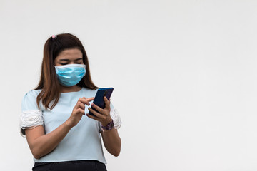 A woman wearing a mask with a mobile phone near a concrete wall.