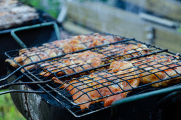 Outdoor barbecue, chicken meat is cooked on coals in smoke.