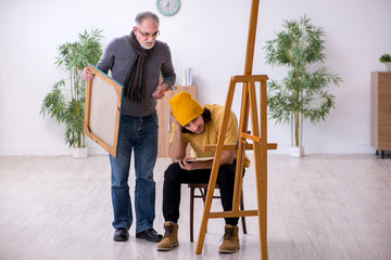 Young man taking lesson from old painter