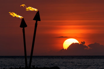 Tiki torches silhouetted at sunset, Maui, Hawaii.