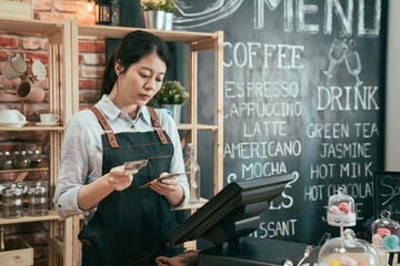 elegant young woman cafe owner wear apron standing in counter counting customers money earn today....